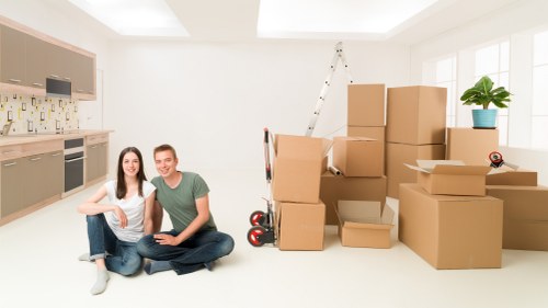 Professional movers carrying furniture through a Brondesbury flat entrance